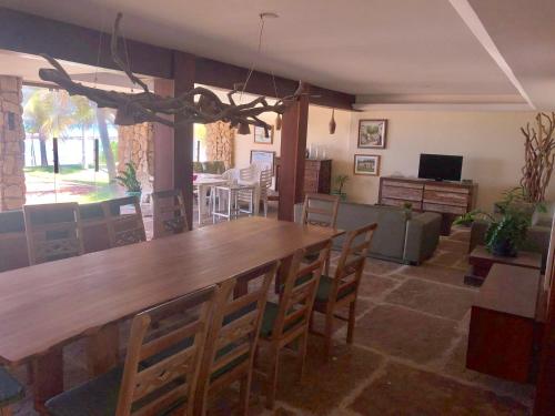 a dining room with a large wooden table and chairs at Linda casa à beira mar in Barra de São Miguel
