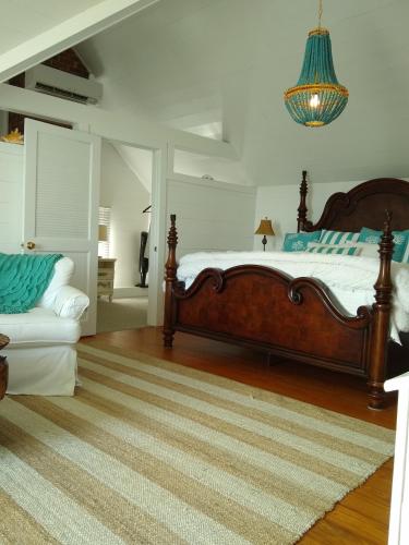 a bedroom with a large bed and a chandelier at Surf Song Bed & Breakfast in Tybee Island