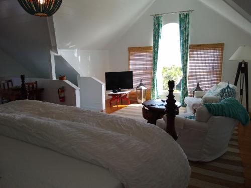 a bedroom with a bed and a couch and a tv at Surf Song Bed & Breakfast in Tybee Island