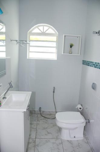 a white bathroom with a toilet and a sink at Pousada Happy Inn in Campinas