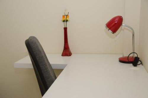 a white desk with a red vase and a red lamp at Pousada Happy Inn in Campinas