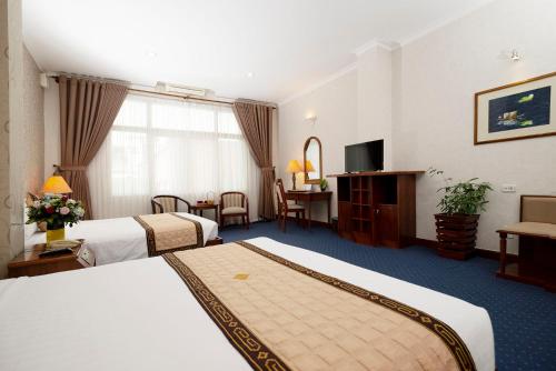 a hotel room with two beds and a television at Grand Hotel Vung Tau in Vung Tau