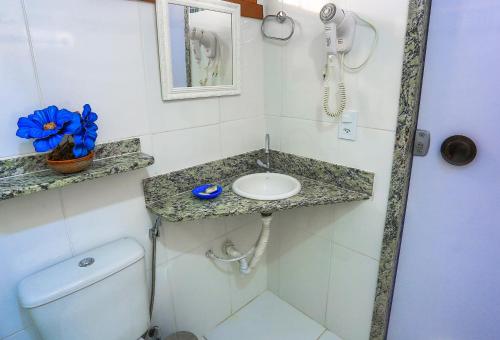 a bathroom with a sink and a toilet and a phone at Pousada dos Corais in Itaúnas