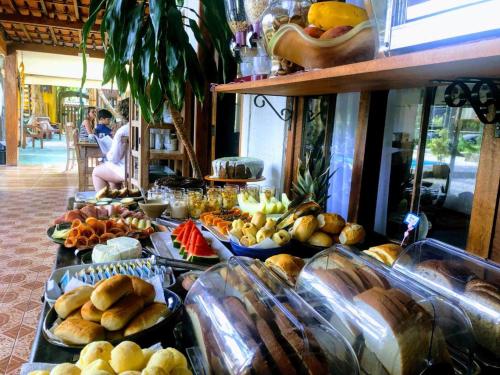 una línea de buffet con diferentes tipos de pan y fruta en Pousada Papaya Container, en Ubatuba