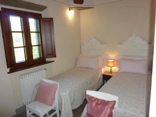 a bedroom with two beds and a chair and a window at VILLA Podere IL GIARDINO in Castiglion Fiorentino