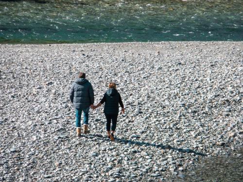 a man and woman walking on a rocky beach at Wonderland Makarora Lodge in Makarora
