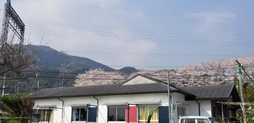 a white house with mountains in the background at KAFUU guesthouse+cafe in Kashiba