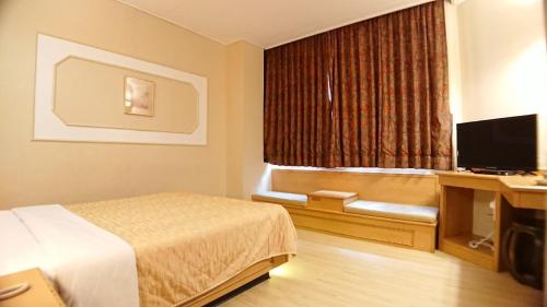 a hotel room with a bed and a flat screen tv at Yes Hotel in Chiayi City