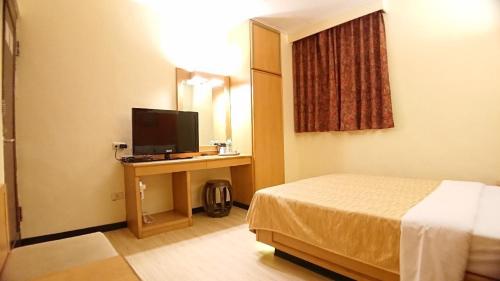 a hotel room with a bed and a television at Yes Hotel in Chiayi City