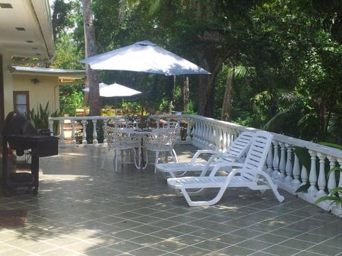 two white chairs and an umbrella on a patio at Hibiscus House Bed and Breakfast in Contadora