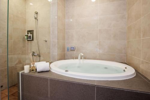 a bath tub in a bathroom with a shower at Duo Romance Hotel in Hualien City