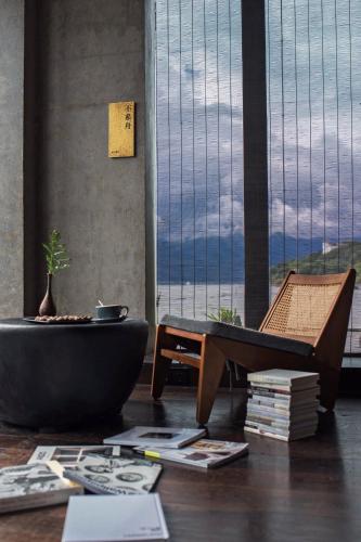 a room with a table and a chair and a large window at Yakamoz Erhai Hotel in Dali