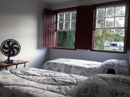 オウロ・プレットにあるCasa Vermelhaのベッドが2つと窓が2つある寝室