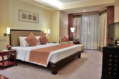 a bedroom with a large bed and a television at Rama Gardens Hotel Bangkok in Bangkok
