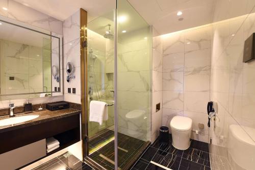 a bathroom with a shower and a toilet and a sink at Ramada Plaza by Wyndham Wenzhou in Wenzhou