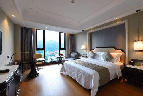 a bedroom with a large bed with a large window at Ramada Plaza by Wyndham Wenzhou in Wenzhou