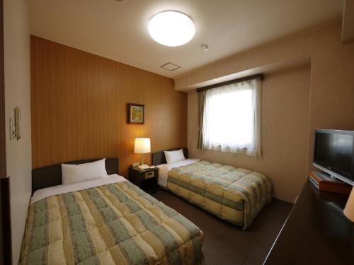 a hotel room with two beds and a flat screen tv at Hotel Route-Inn Court Minami Matsumoto in Matsumoto