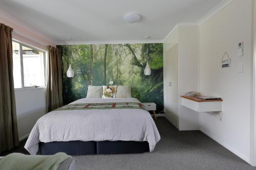 a bedroom with a bed with a painting on the wall at Aden Motel in Te Anau