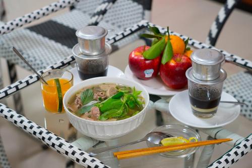 a table topped with a bowl of soup and fruit at Ben Thanh Retreats Hotel in Ho Chi Minh City