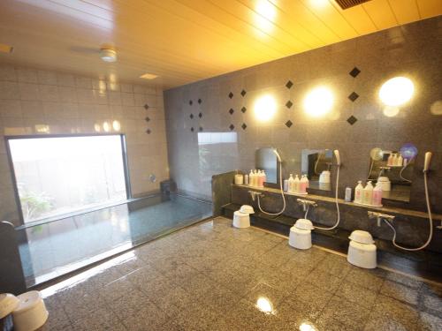 a bathroom with a sink and a mirror in a room at Hotel Route-Inn Ashikaga Ekimae in Ashikaga