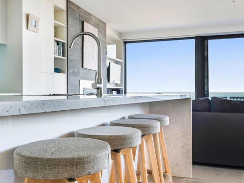 a kitchen with bar stools and a counter with a couch at Aqua Mist Seascape in Port Fairy