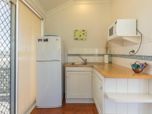a kitchen with a white refrigerator and a sink at Amhurst Cottage in Port Fairy