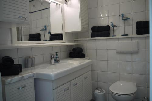 une salle de bain avec un lavabo, des toilettes et un miroir dans l'établissement Bollmann, à Westerland