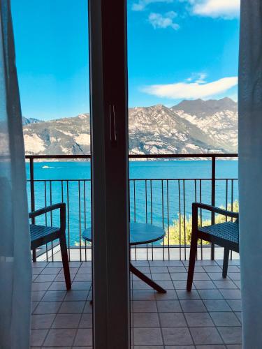a balcony with chairs and a view of the water at Hotel Villa Carmen in Malcesine