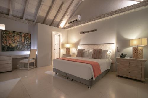 Hotel Noi Cartagena 1860 في كارتاهينا دي اندياس: غرفة نوم مع سرير كبير مع مكتب وسرير six sidx sidx
