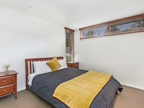 a bedroom with a bed with a yellow blanket at Castwood Villa 1 in Port Fairy