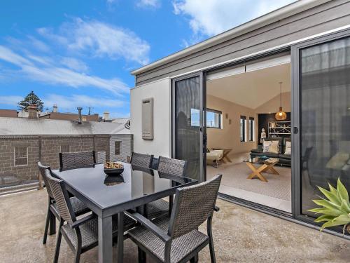 a dining room with a table and chairs on a patio at Chimneys On Bank in Port Fairy