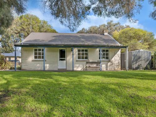 a small white house with a grass yard at Corella Cottage in Port Fairy