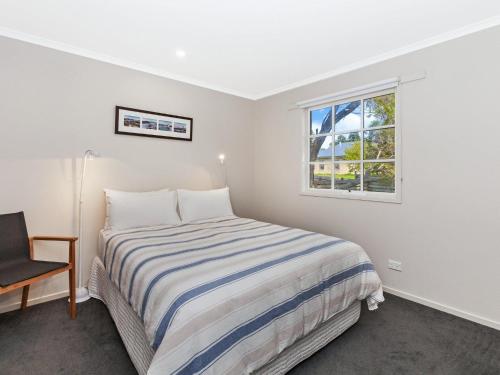 a bedroom with a bed and a window at Corella Cottage in Port Fairy