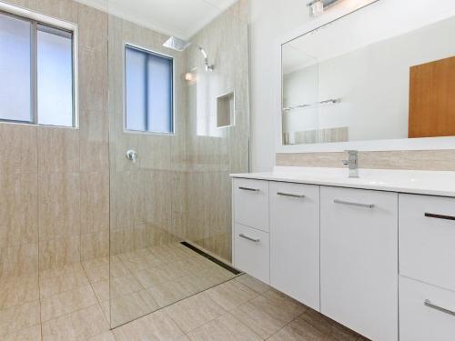 Un baño blanco con ducha y lavabo. en East Beach House, en Port Fairy