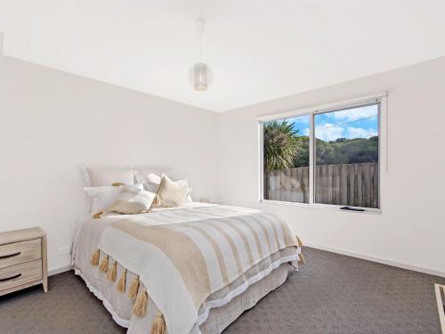 a white bedroom with a bed and a window at Escape 2 Brophy in Port Fairy