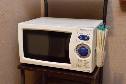 a white microwave sitting on a table with chopsticks at La Vista Furano Hills Natural Hot Spring in Furano