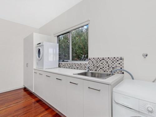 a white kitchen with a sink and a microwave at Escape 2 Brophy in Port Fairy