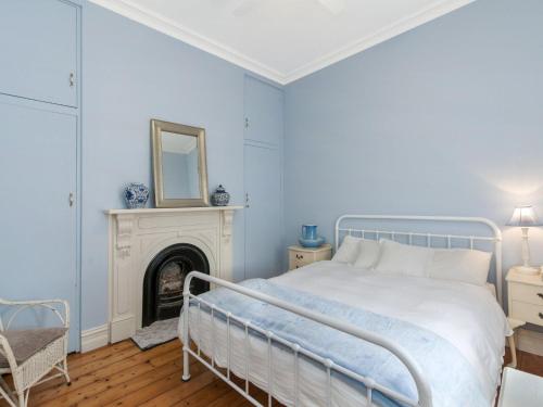 a blue bedroom with a bed and a fireplace at Ginabella in Port Fairy