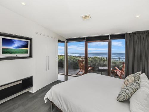 a bedroom with a large bed and a large window at Hearns Beachside Villa 1 in Port Fairy