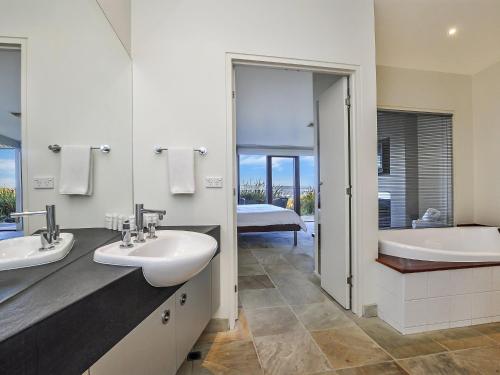 y baño con 2 lavabos, bañera y ducha. en Hearns Beachside Villa 4, en Port Fairy