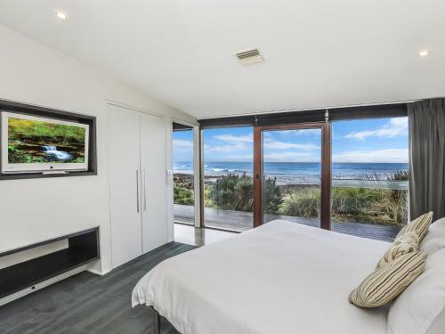 a bedroom with a large bed and a large window at Hearns Beachside Villa 2 in Port Fairy