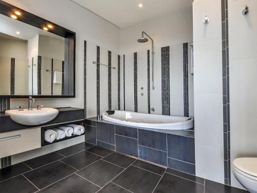 a bathroom with two sinks and a tub and a toilet at Hearns Beachside Villa 3 in Port Fairy