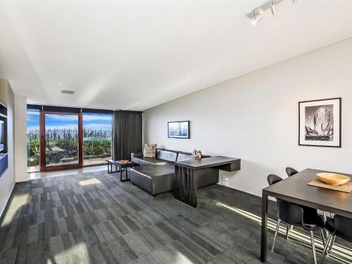 a living room with white walls and a table and chairs at Hearns Beachside Villa 3 in Port Fairy