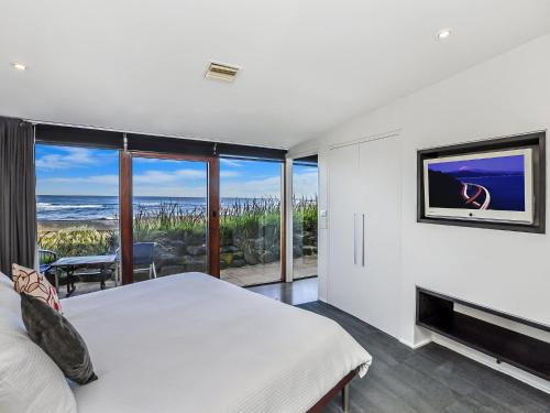 a bedroom with a bed and a view of the ocean at Hearns Beachside Villa 3 in Port Fairy