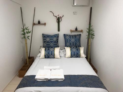a bedroom with a bed with blue and white pillows at Arts Candy Sapporo-Villa Nakajima in Sapporo
