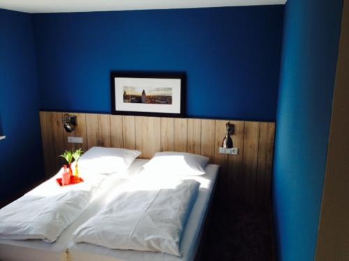 a blue bedroom with a bed with white sheets at Dock1 in Regensburg