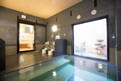 a swimming pool in a bathroom with a large window at Hotel Route-Inn Morioka Minami Inter in Morioka