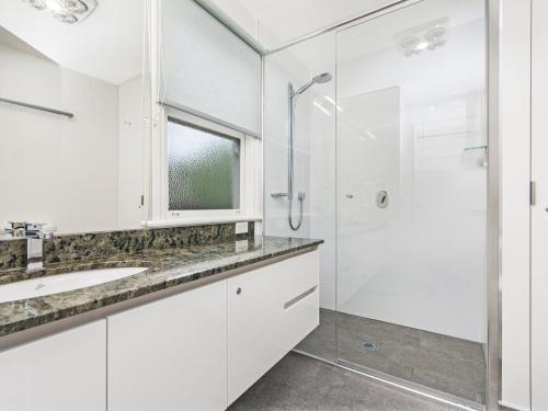 a white bathroom with a shower and a sink at Johanssons Perch Cottage in Port Fairy
