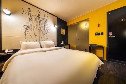 a large white bed in a room with yellow walls at Guri Lexy Hotel in Guri