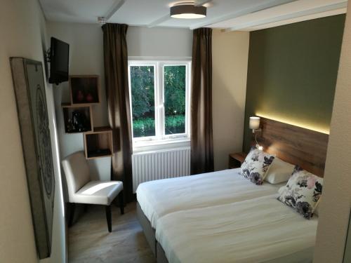 1 dormitorio con 1 cama, 1 silla y 1 ventana en Hotel Kasteel de Essenburgh, en Hierden